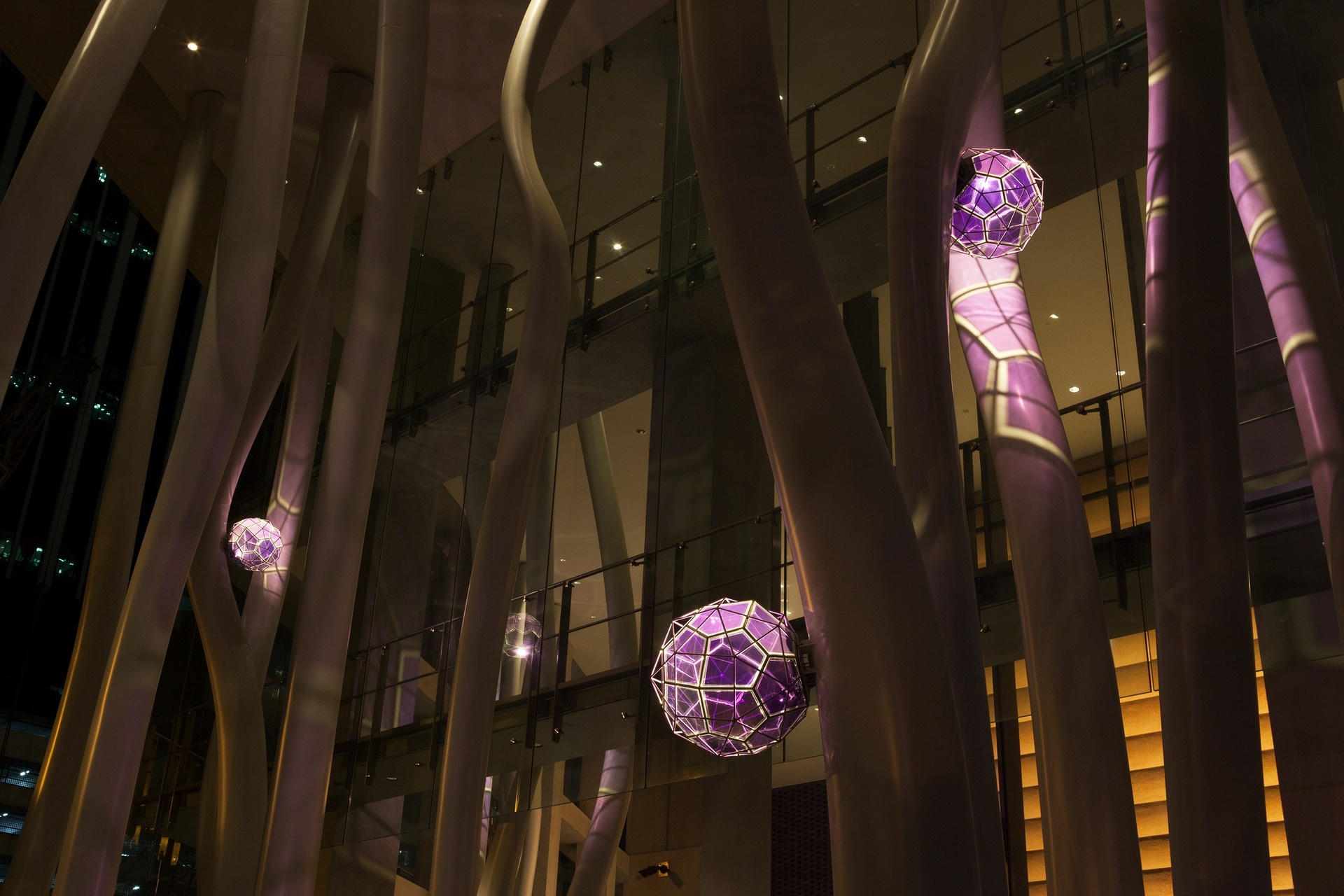 Purple spheres strung along curved metal poles in an atrium.