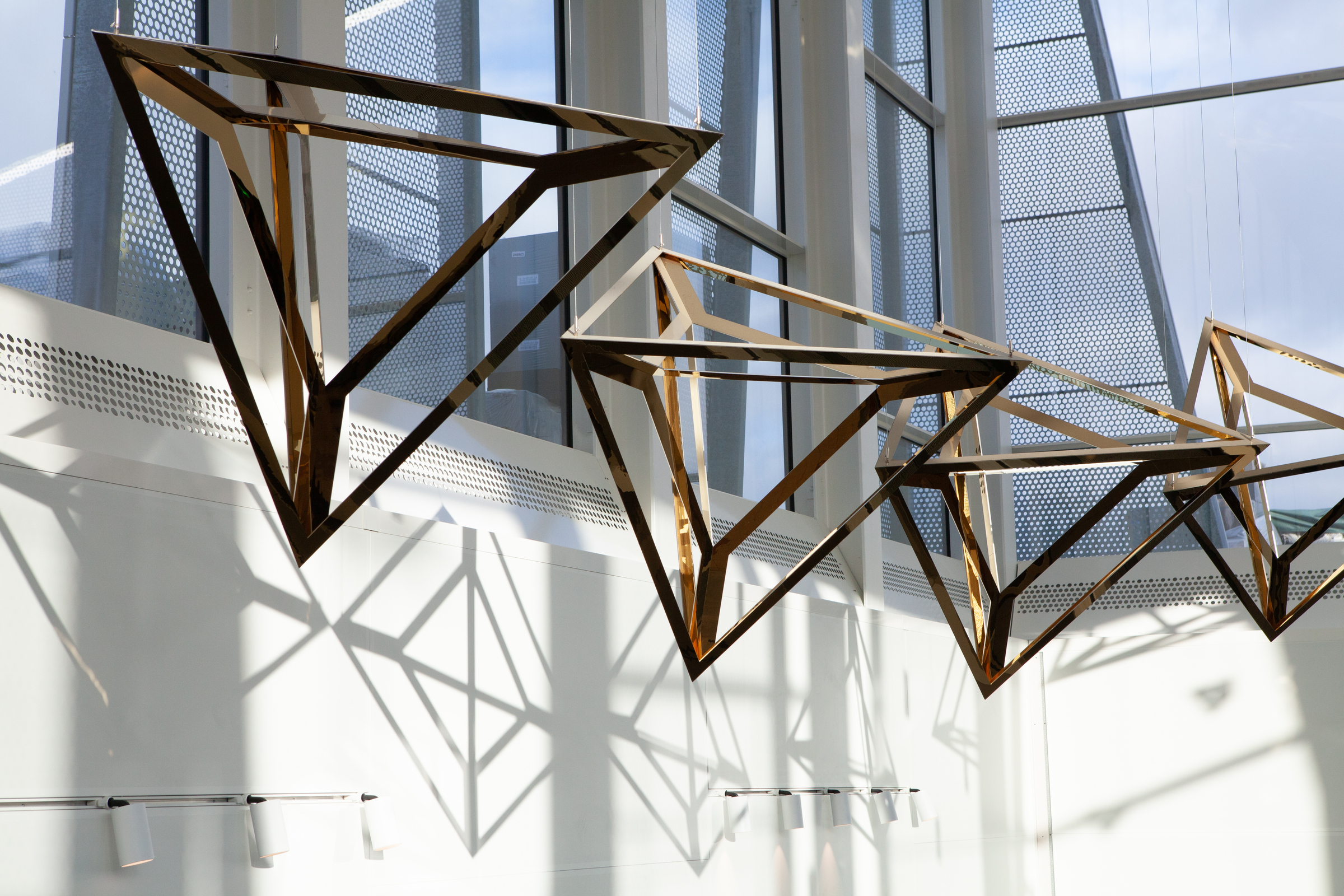 A series of wooden geometric structures hanging in an indoor space.