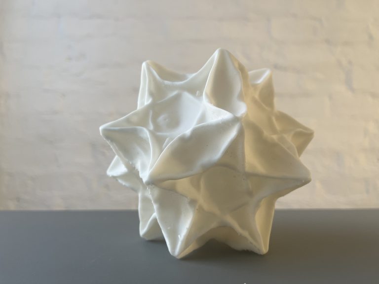 Ceramic sculpture with rough texture on pedestal.