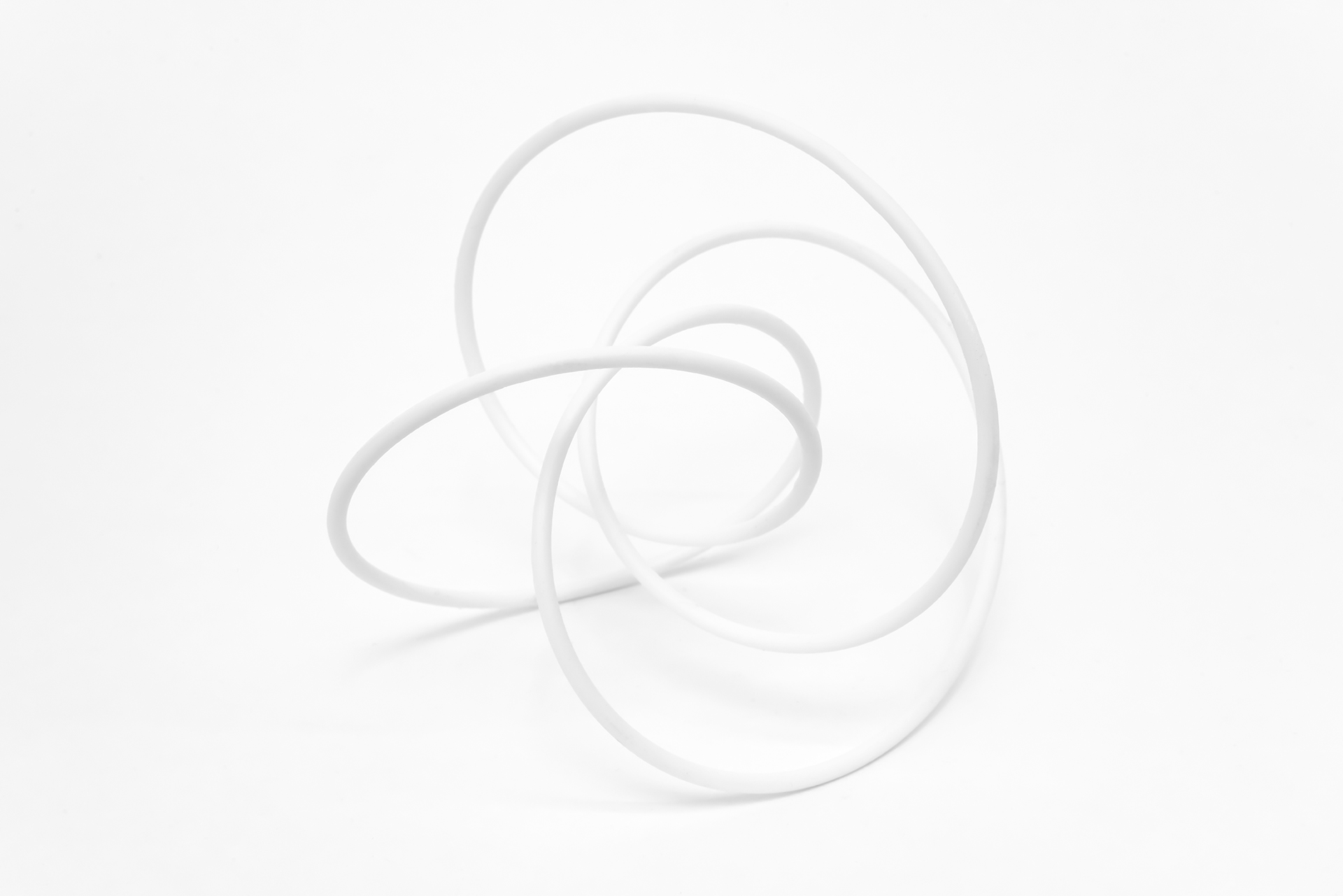 The image displays a tangled knot of 3d printed resin, showcasing its intricate patterns and interweaving forms.