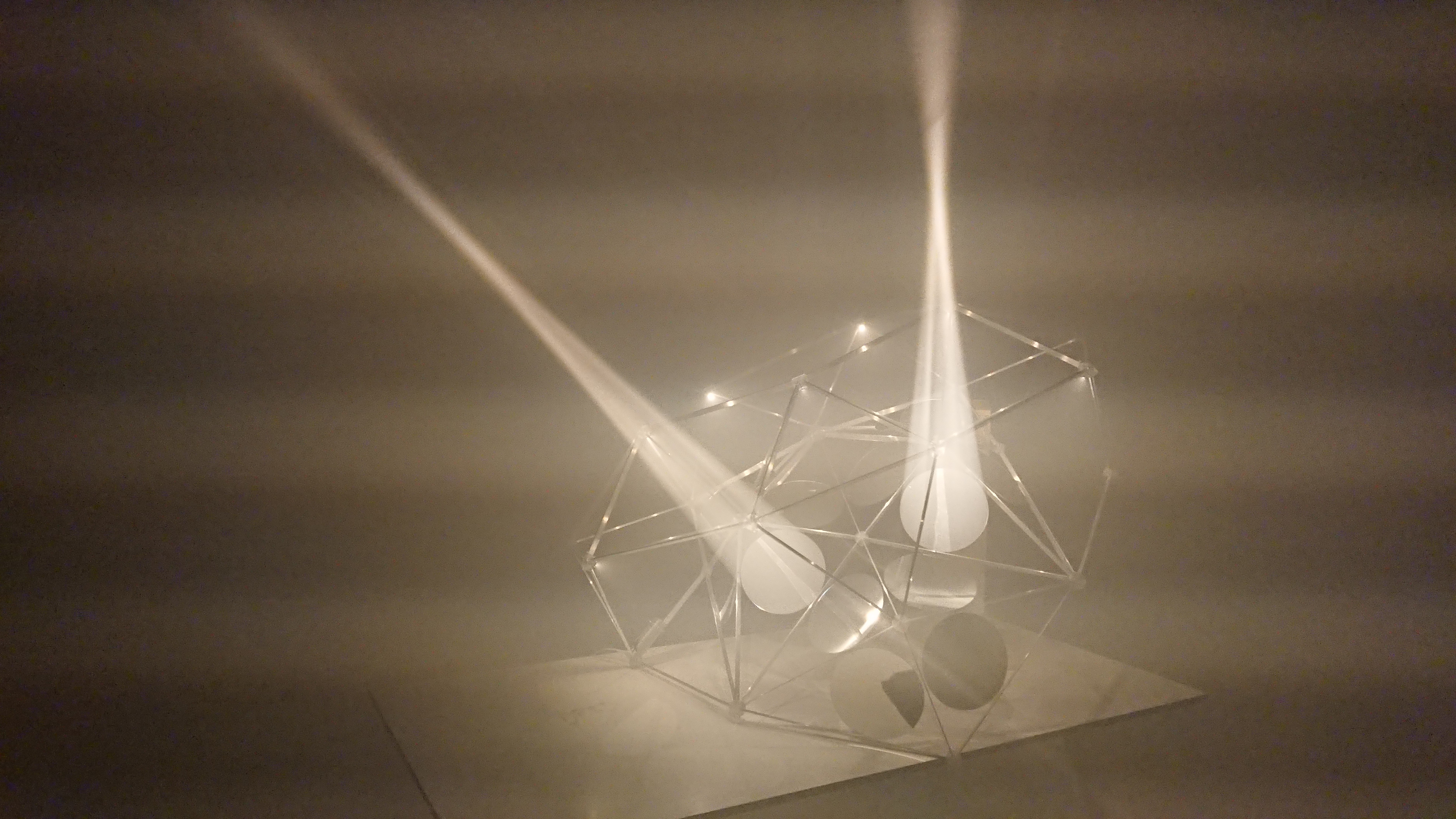 A sculpture of resin and wire forming geometric structures, possibly a representation of parabolic mirrors on polyhedral faces.