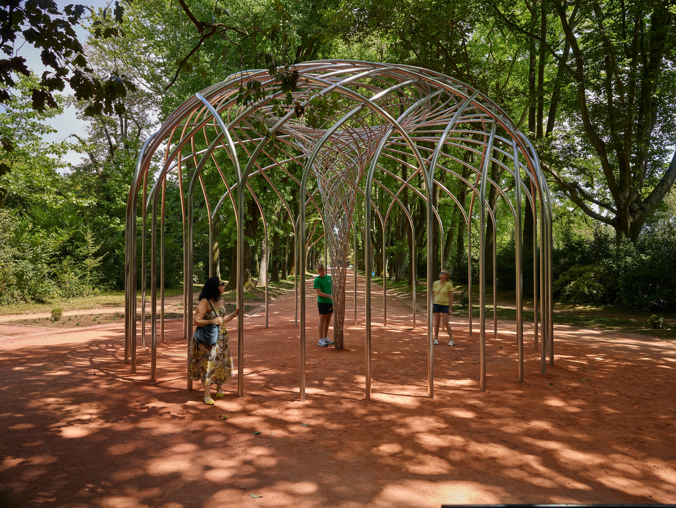 Metal structure with spiral design creates a walkway for people to pass through.