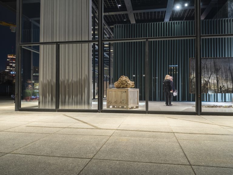 Sand sculpture on pedestal in gallery at night.