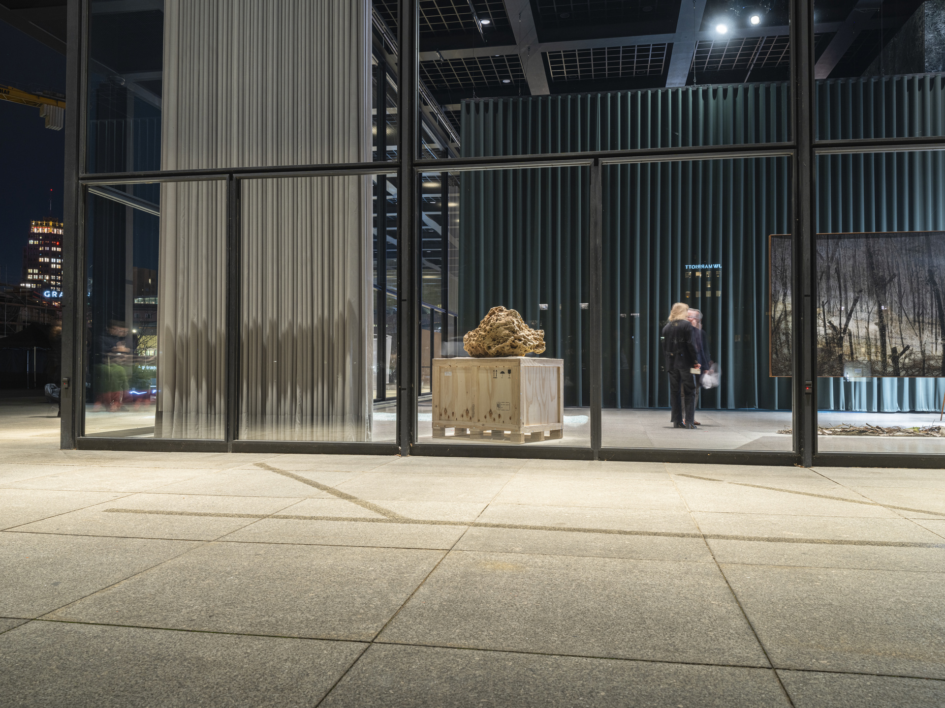 Sand sculpture on pedestal in gallery at night.