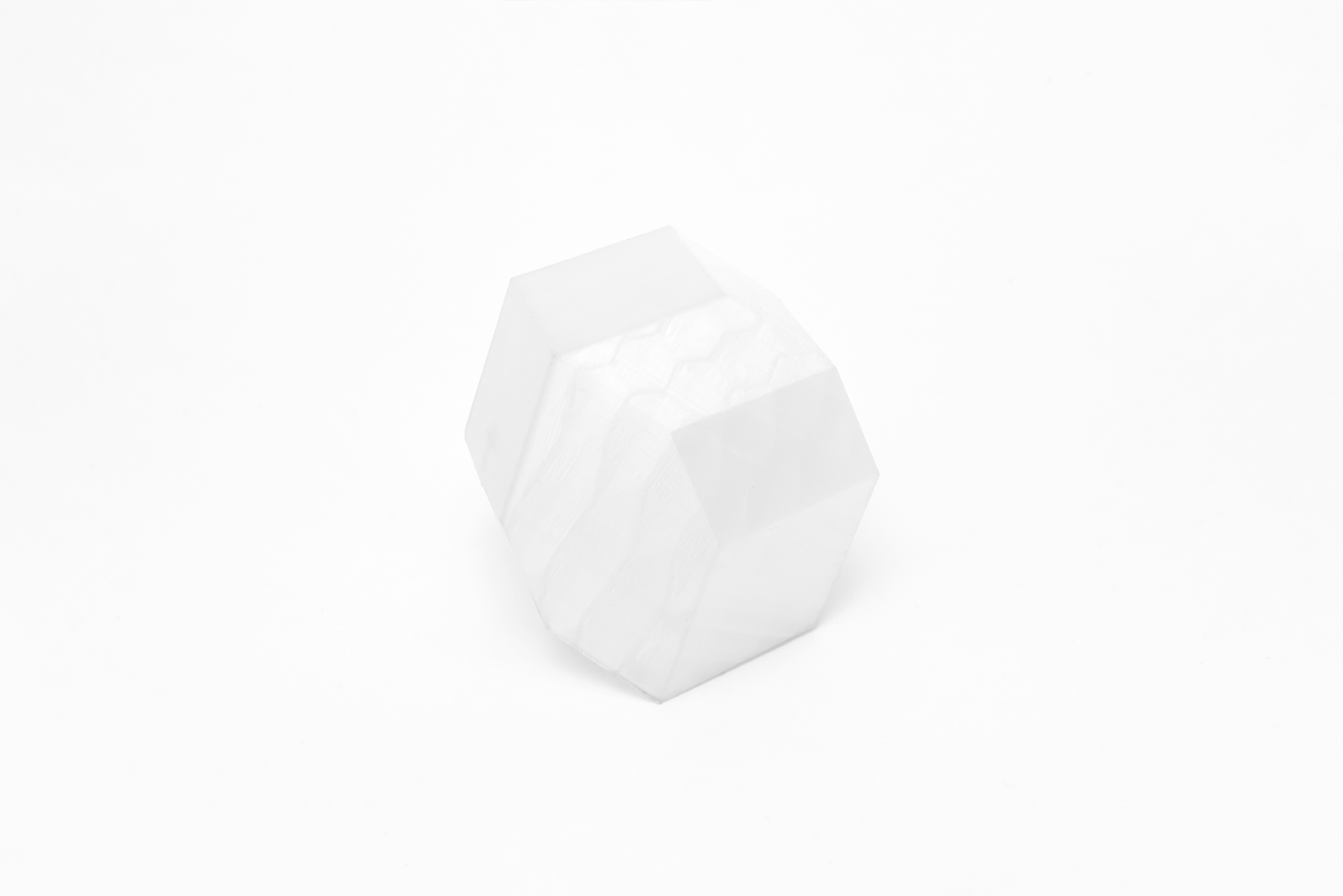 White 3D printed resin cube with rough texture on a white surface.