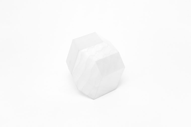 Solid white resin sculpture of quasibrick geometry, isolated on plain gray background.