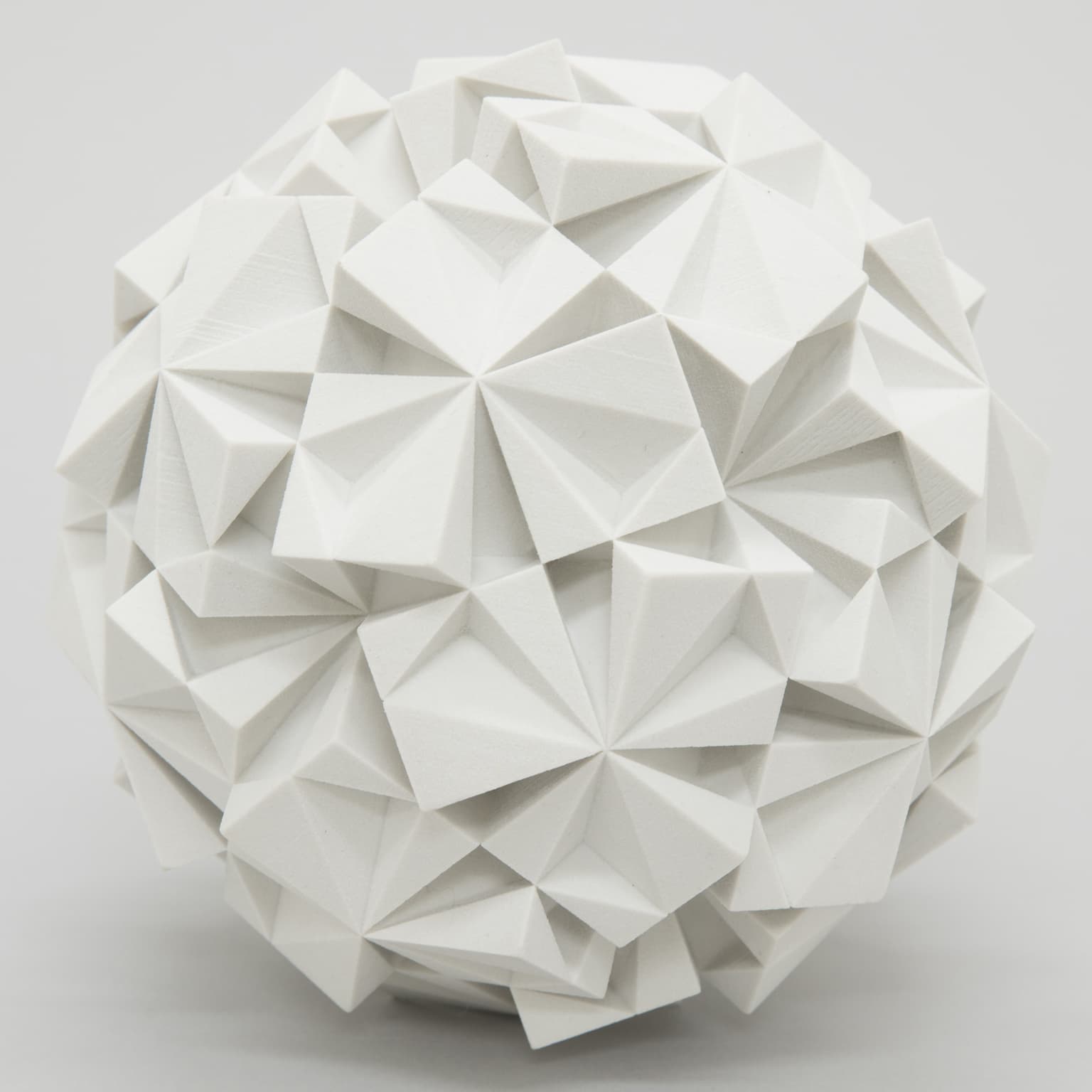 White plaster sculpture of an icosahedral dodecahedron with intricate geometric patterns.