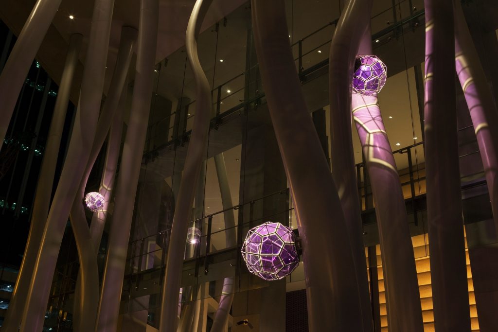 Steel columns and purple glass spheres hang in a modern building.