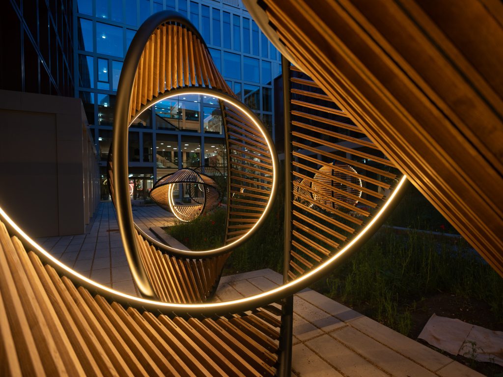 Journey of Circumference installation, made of painted stainless steel, wood, and lighting, is located in an urban setting.