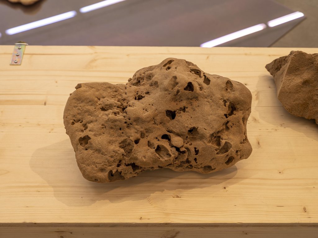 A 3D printed sand sculpture sits on a wooden surface in "Field of Fragments.