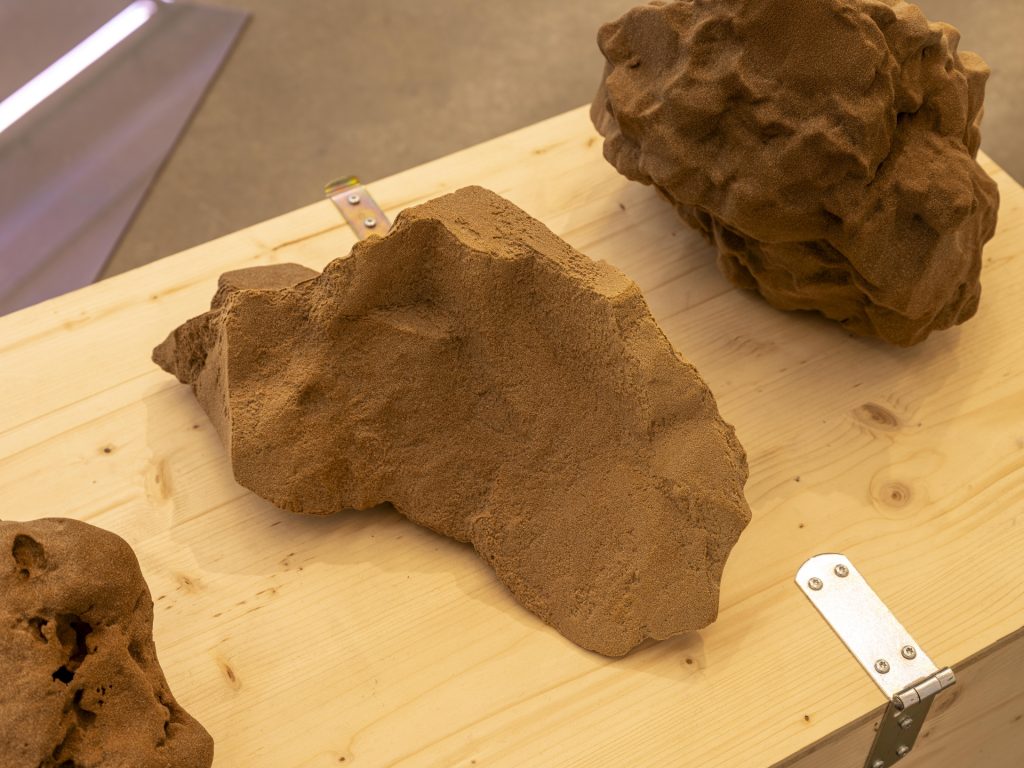 3D printed sand sculptures sit on a wooden table in 'Field of Fragments' exhibition.