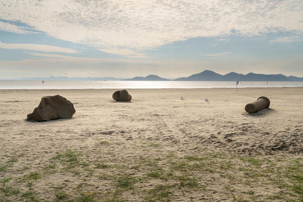 Tidal Memories" sand sculptures sit on a beach, showcasing large sand grains.