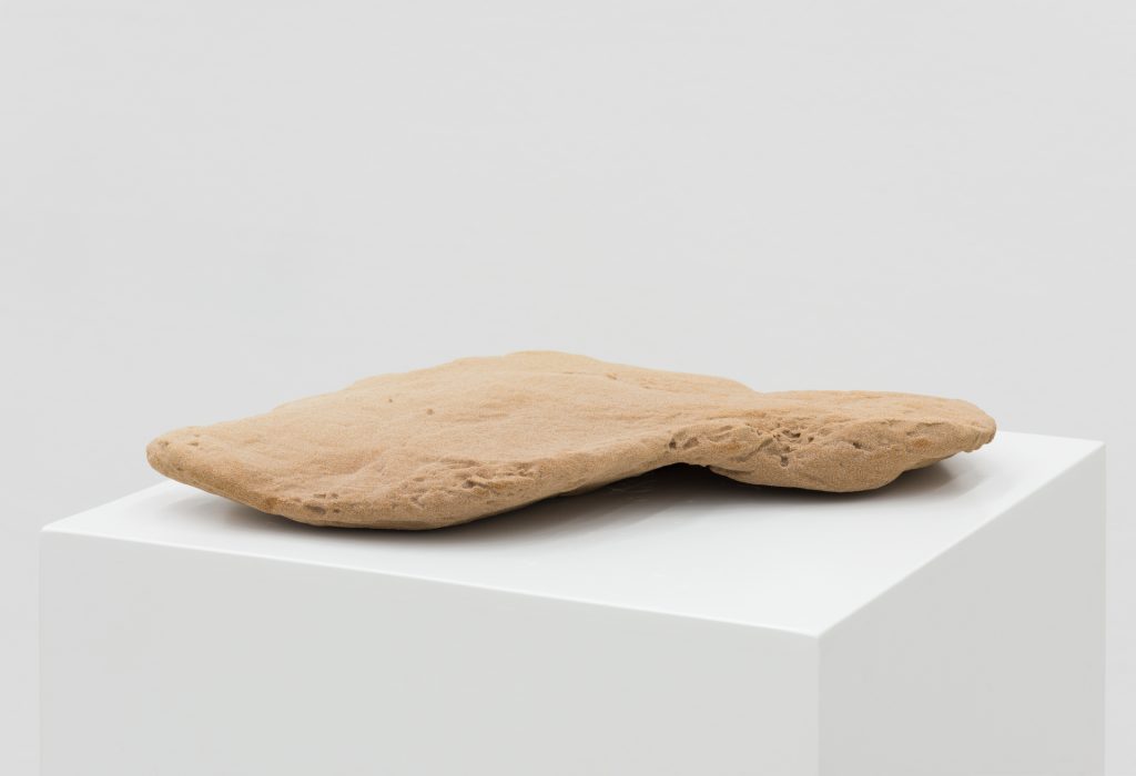 A 3D printed sand sculpture sits on a white pedestal.