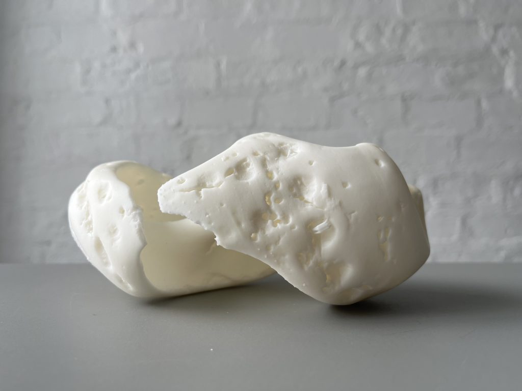 White 3D printed resin object sits on gray surface.