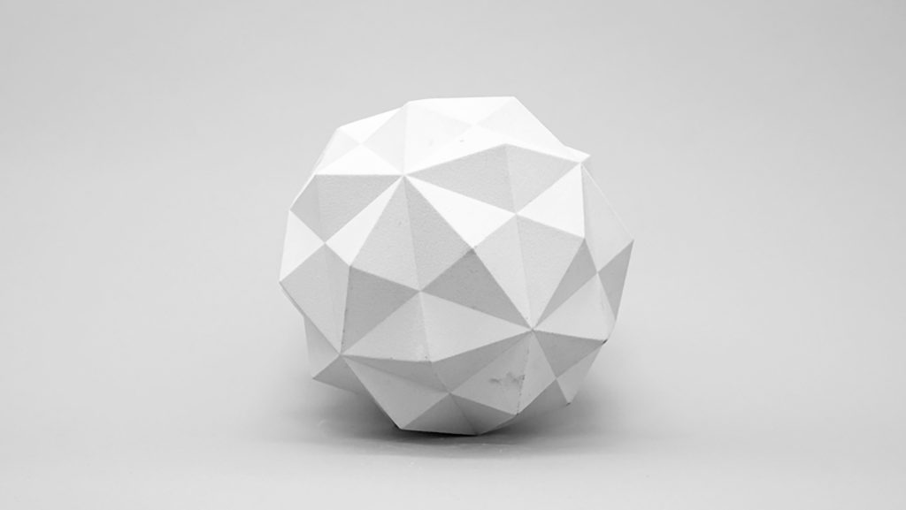 White 3D printed resin sphere sits on a white surface.