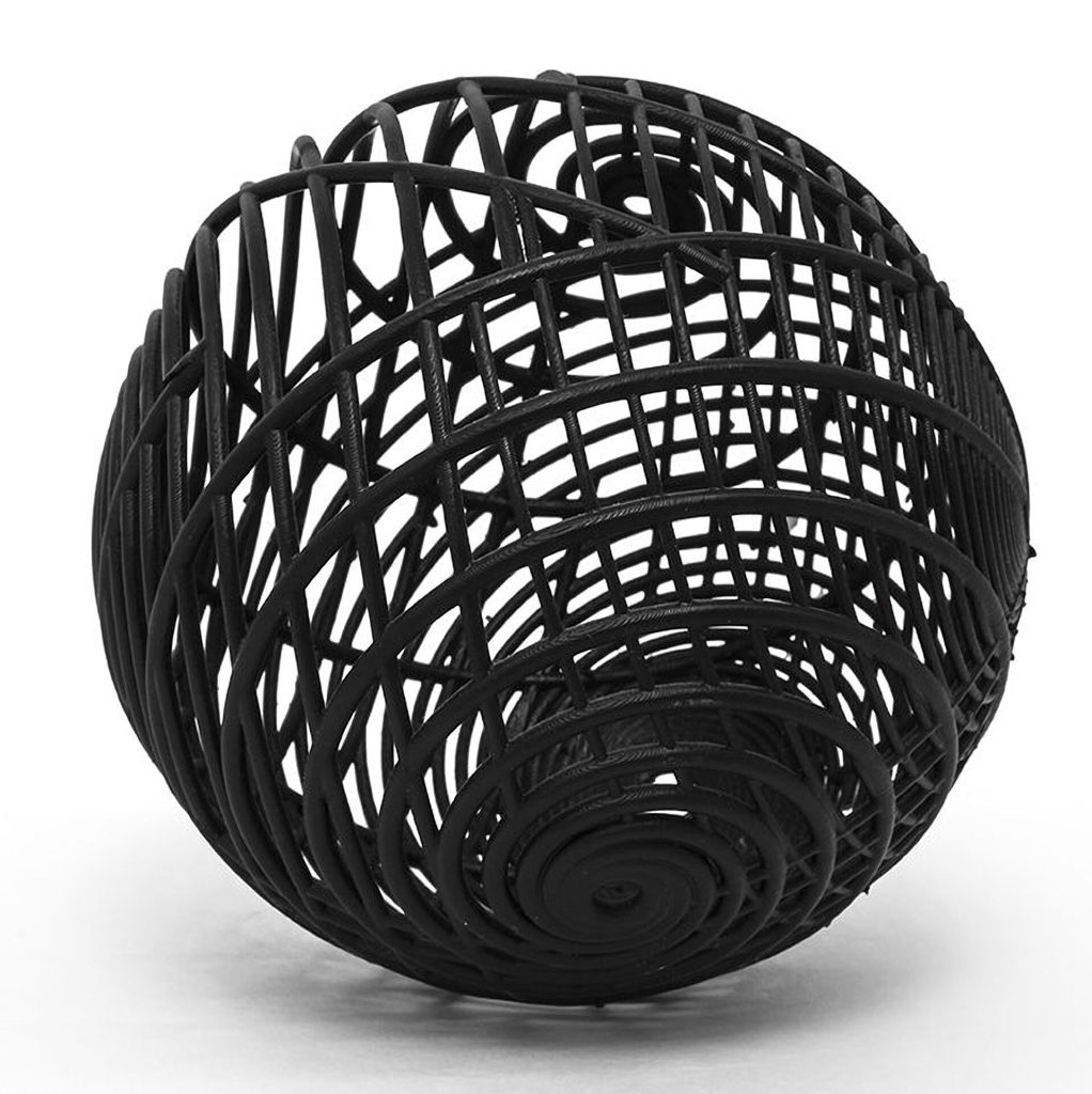 A black 3D printed resin sphere sits on a white surface with spiral paneling.