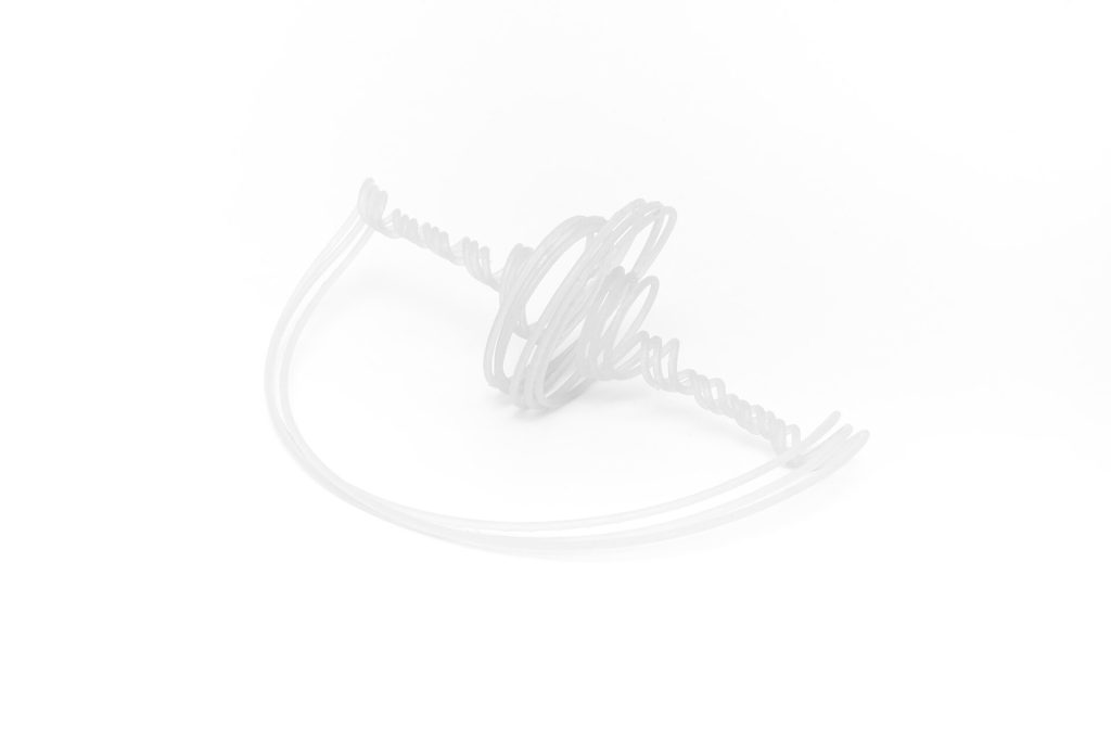 A white, 3D-printed resin object with coiled tubes forms a spherical spiral structure on a plain background.