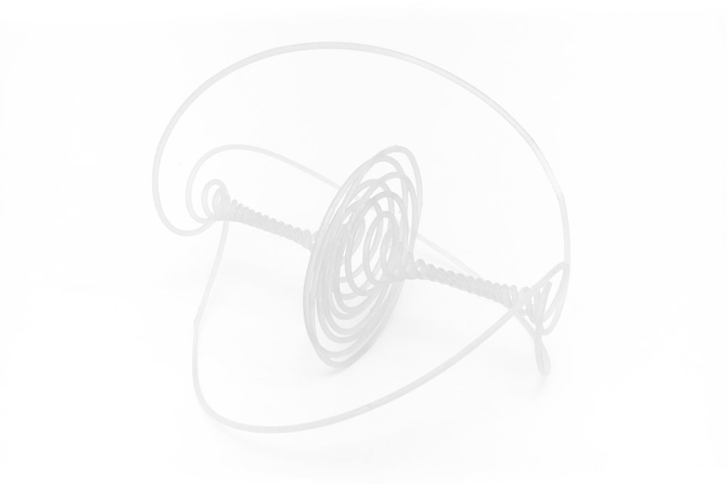 A white, 3D-printed resin sculpture with a coiled central spiral and curved outer frame sits on a white surface.