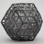 A 3D printed resin rhombic structure sits on a white surface.