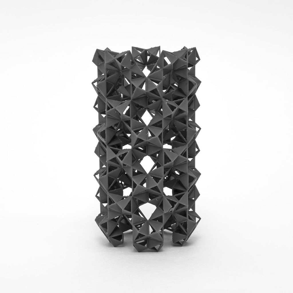 A 3D-printed resin model of stacked interlocking rings sits on a white surface.