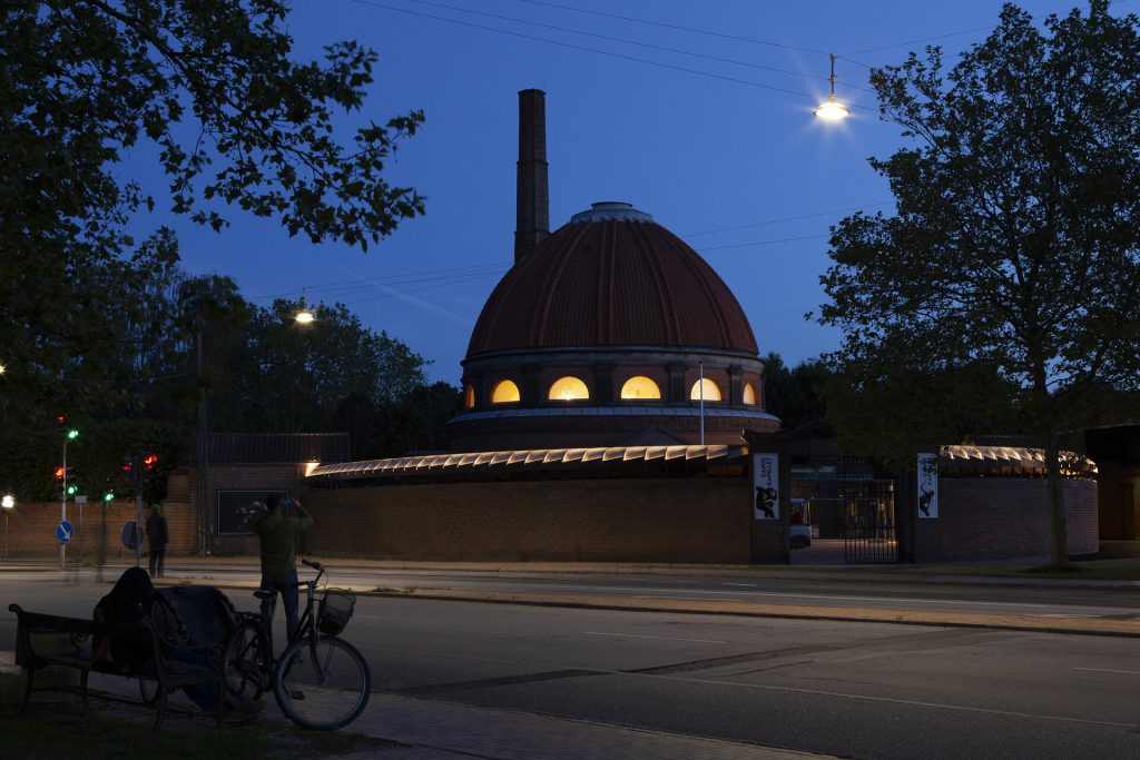 A brick dome with a chimney sits behind a wall with a rotating mirror assembly and time-controlled lighting.