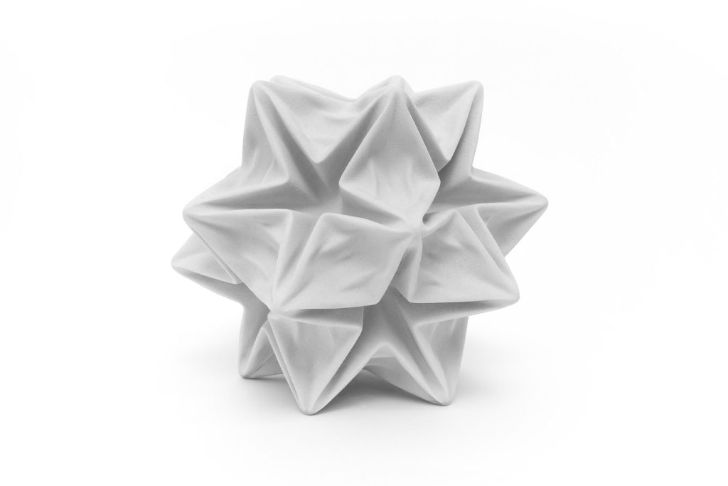 A white 3D-printed resin stellated polyhedron deforms under simulated deep ocean pressure on a white background.