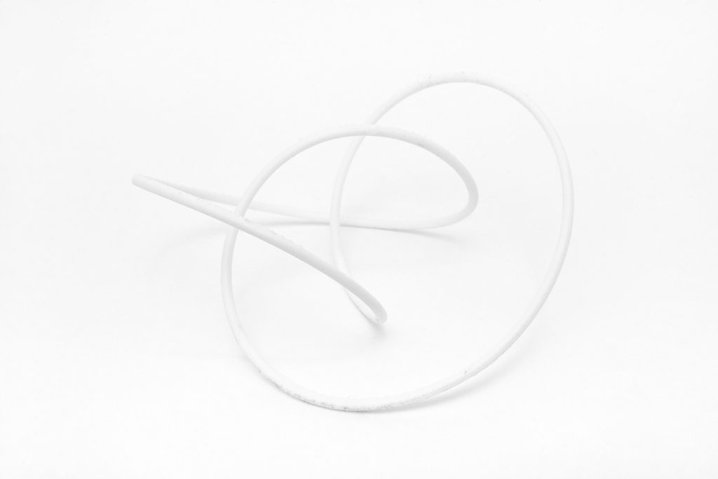A white, 3D-printed resin knot model rests on a plain surface.