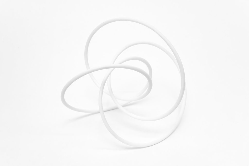 A white 3D-printed resin knot sculpture sits on a plain surface.