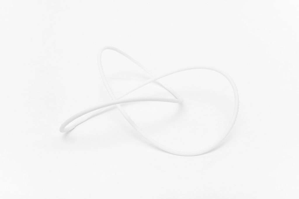A white, 3D-printed resin knot model rests on a plain surface.