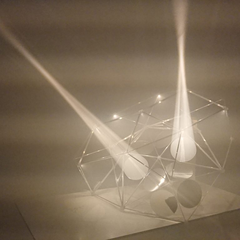 A 3D printed resin polyhedron holds parabolic mirrors that project light cones.
