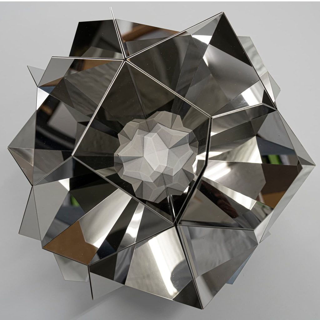 A stainless steel and 3D printed resin sculpture forms a mirrored, polyhedral shape with a central resin core.