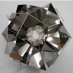 A stainless steel and 3D printed resin sculpture forms a mirrored, polyhedral shape with a central resin core.