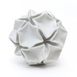 A white 3D-printed plaster model of a deformed rhombic triacontahedron sits on a surface.