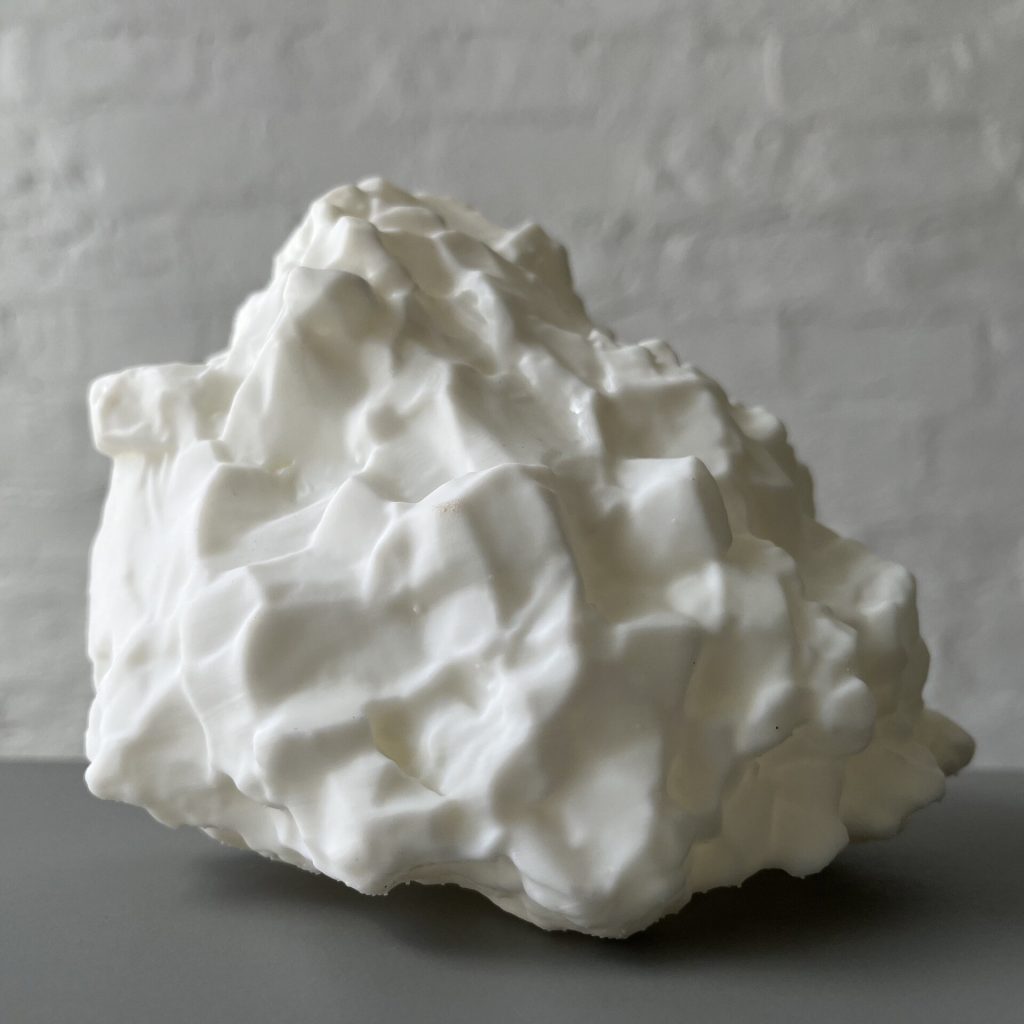 A white 3D printed resin object with a bumpy surface sits on a gray table.