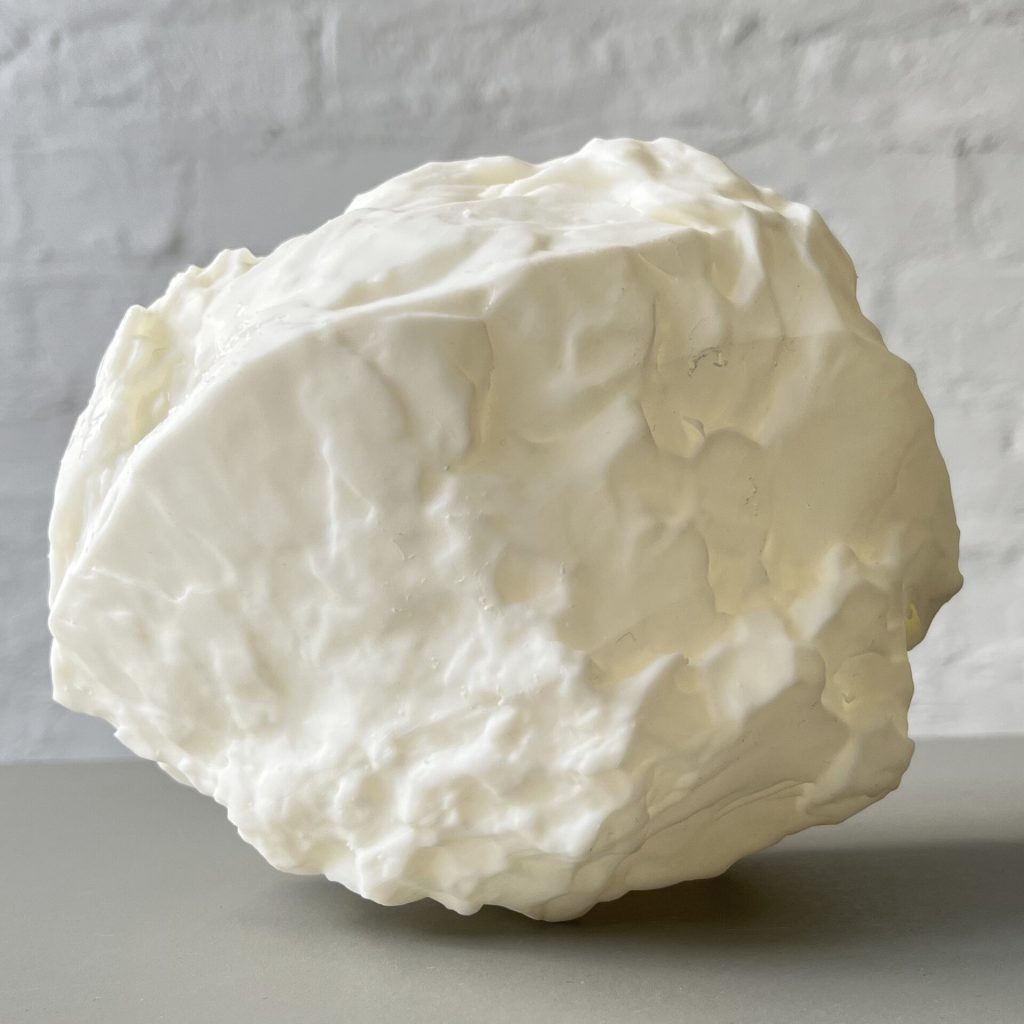 A white 3D printed resin object with a bumpy surface sits on a gray shelf.