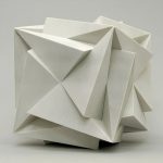 A white 3D-printed sculpture with geometric folds sits on a neutral surface.