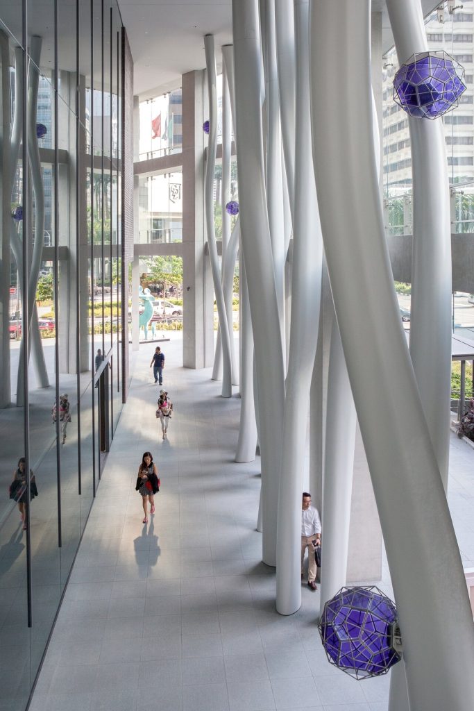 White steel columns and suspended purple glass crystals line a tiled walkway.
