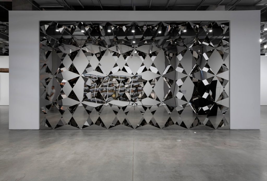 Diamond-shaped stainless-steel mirrors form a cubic wall partition with gaps revealing internal mirrors.
