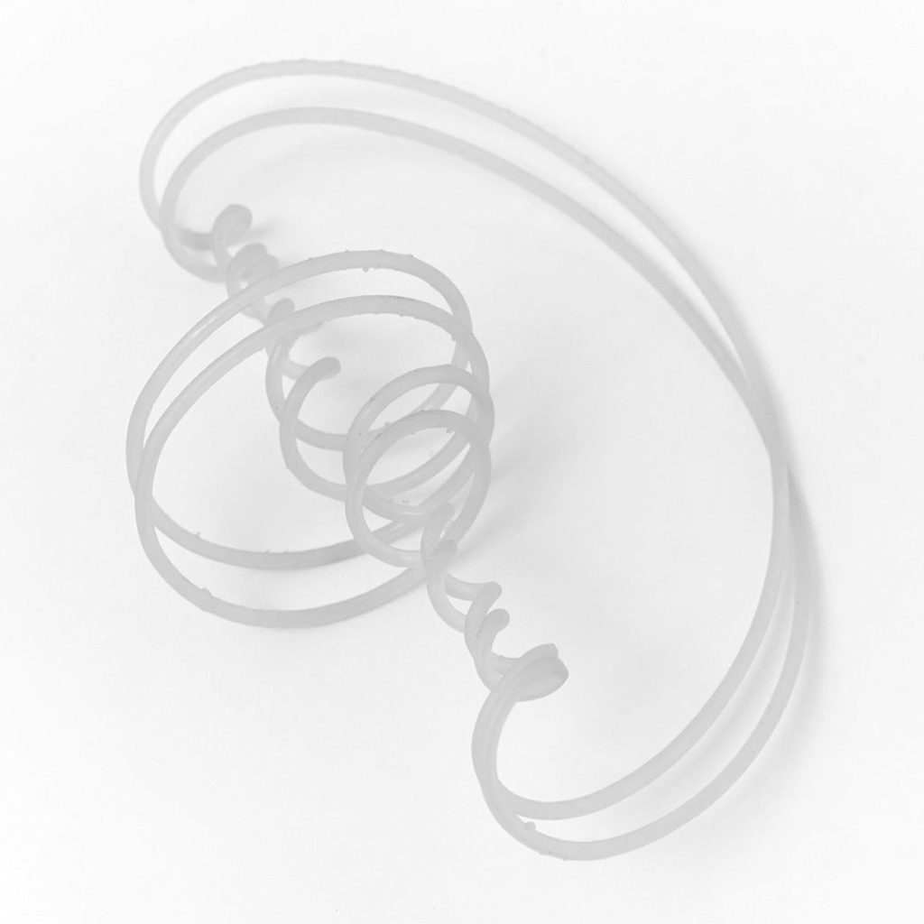 A 3D printed resin tube bends into a double vortex spiral on a white surface.