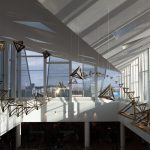 Coated stainless steel tetrahedra hang from wires in a Möbius strip inside a sunlit atrium.