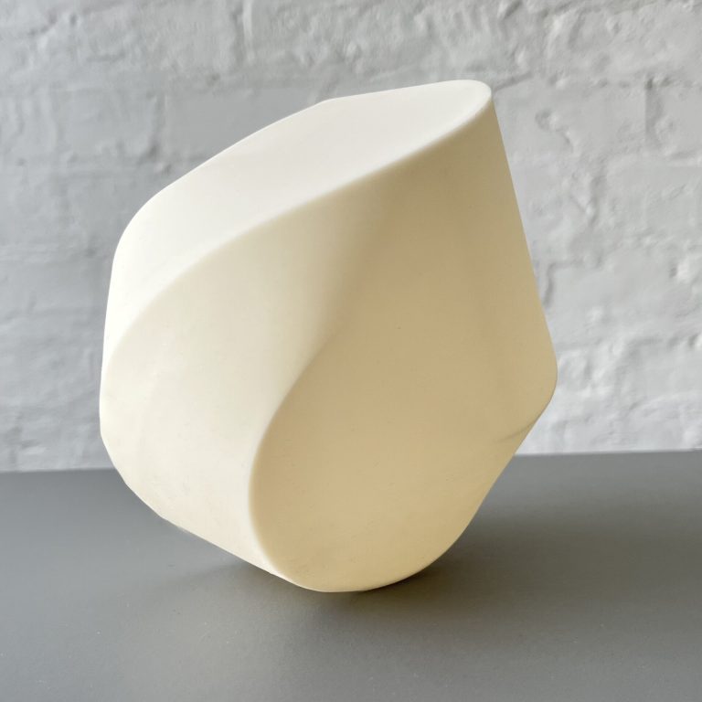 A white 3D printed resin polyhedral structure sits on a gray surface.
