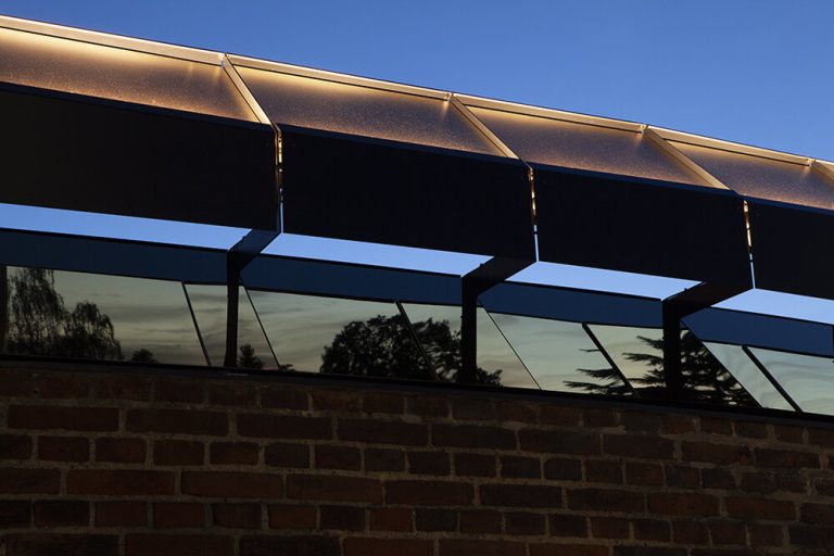 Coated stainless steel panels with time-controlled lighting sit on a brick wall.