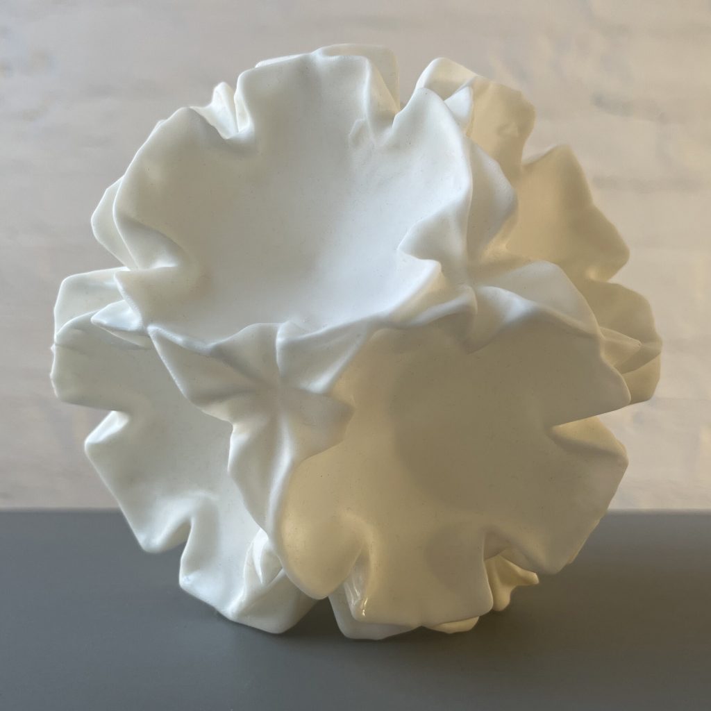A white 3d printed resin sculpture shows a deformed stellated polyhedron.