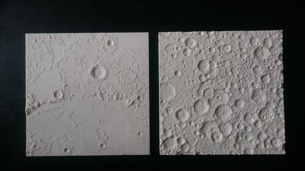 Two white 3d printed resin squares show lunar craters on a black surface.