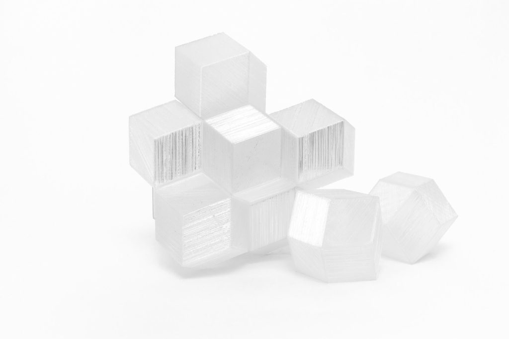 White 3D printed resin cubes form a cluster with two separate dodecahedra on a white background.