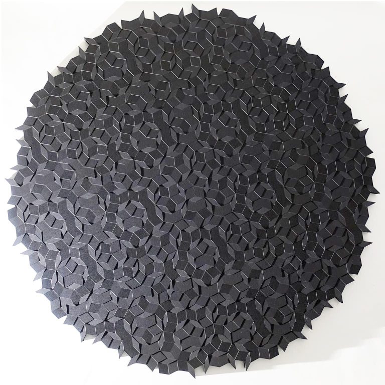A circular 3D-printed resin model of aperiodic subgrouping sits on a white surface.