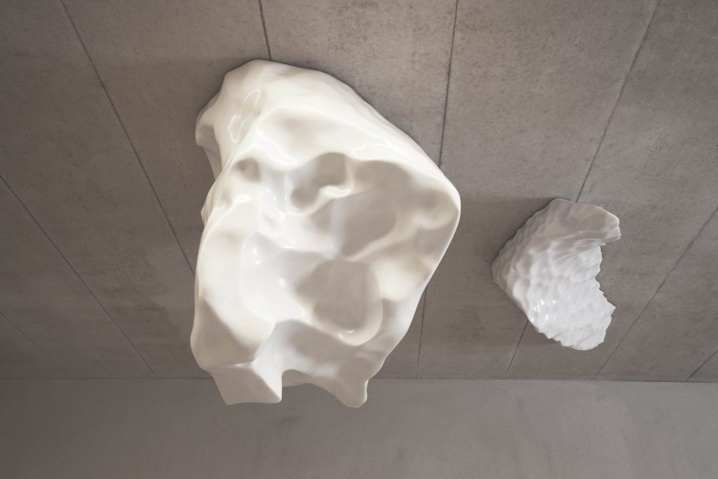 Two white Carrara marble blocks hang from a gray concrete ceiling.