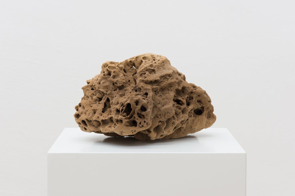 A 3D-printed quartz sand sculpture with porous texture sits on a white pedestal.