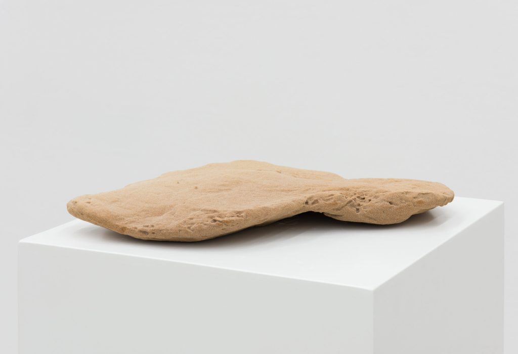 A 3D-printed sand sculpture rests on a white pedestal.