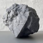 A 3d printed resin object sits on a surface with a rough, sand grain topology.